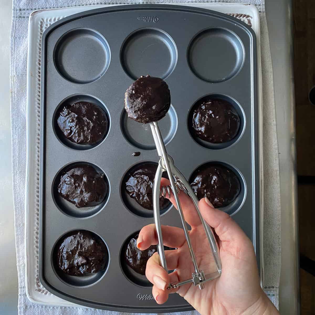 scooping brownie mix into pan