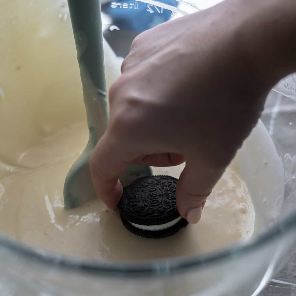 Dipping one side of the Oreo cookie into the cake batter.