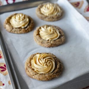 ginger molasses cookies on a baking sheet with pumpkin mousse piped in a swirl pattern on the top