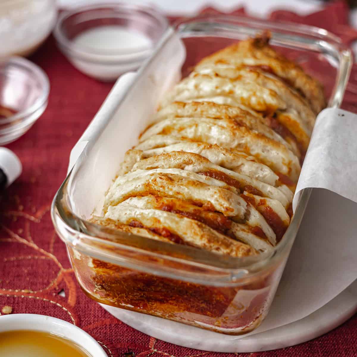 Pumpkin pull apart bread in a parchment-lined loaf pan before baking, showing buttery layers and spiced filling.