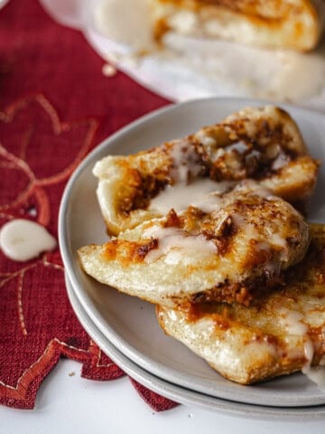Slices of warm pumpkin pull apart bread drizzled with maple glaze on a small white plate.